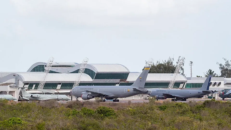 Aeronaves militares cinza estacionadas no pátio da Base Aérea de Natal, com o prédio do terminal ao fundo e vegetação em primeiro plano