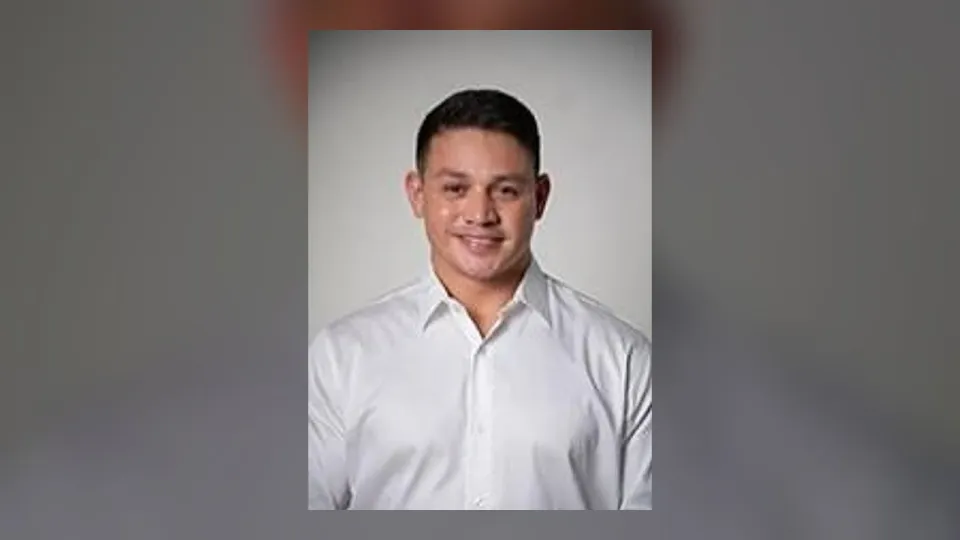 Foto oficial de Cabo Deyvison, de camisa branca, sobre fundo desfocado