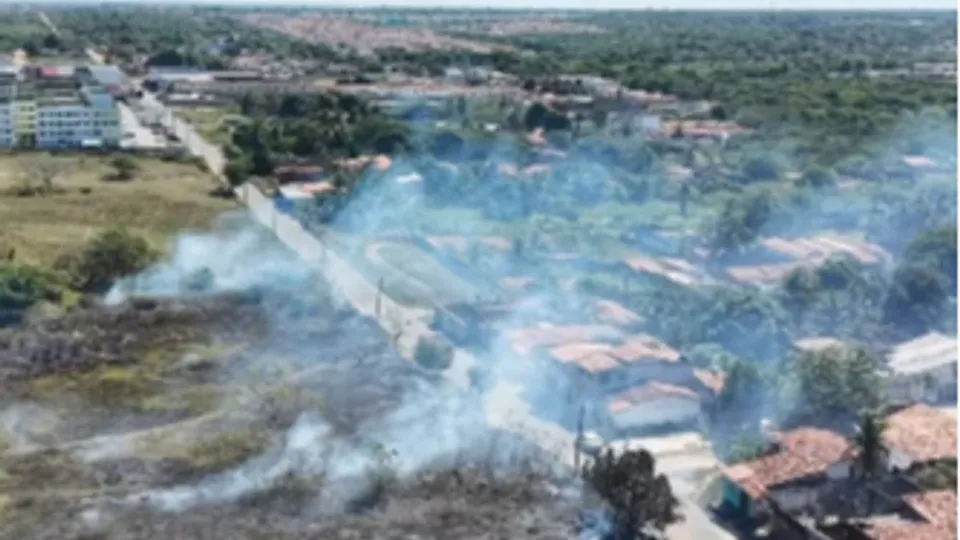Imagem aérea mostra fumaça sobre área de vegetação queimada ao lado de casas em São Gonçalo do Amarante